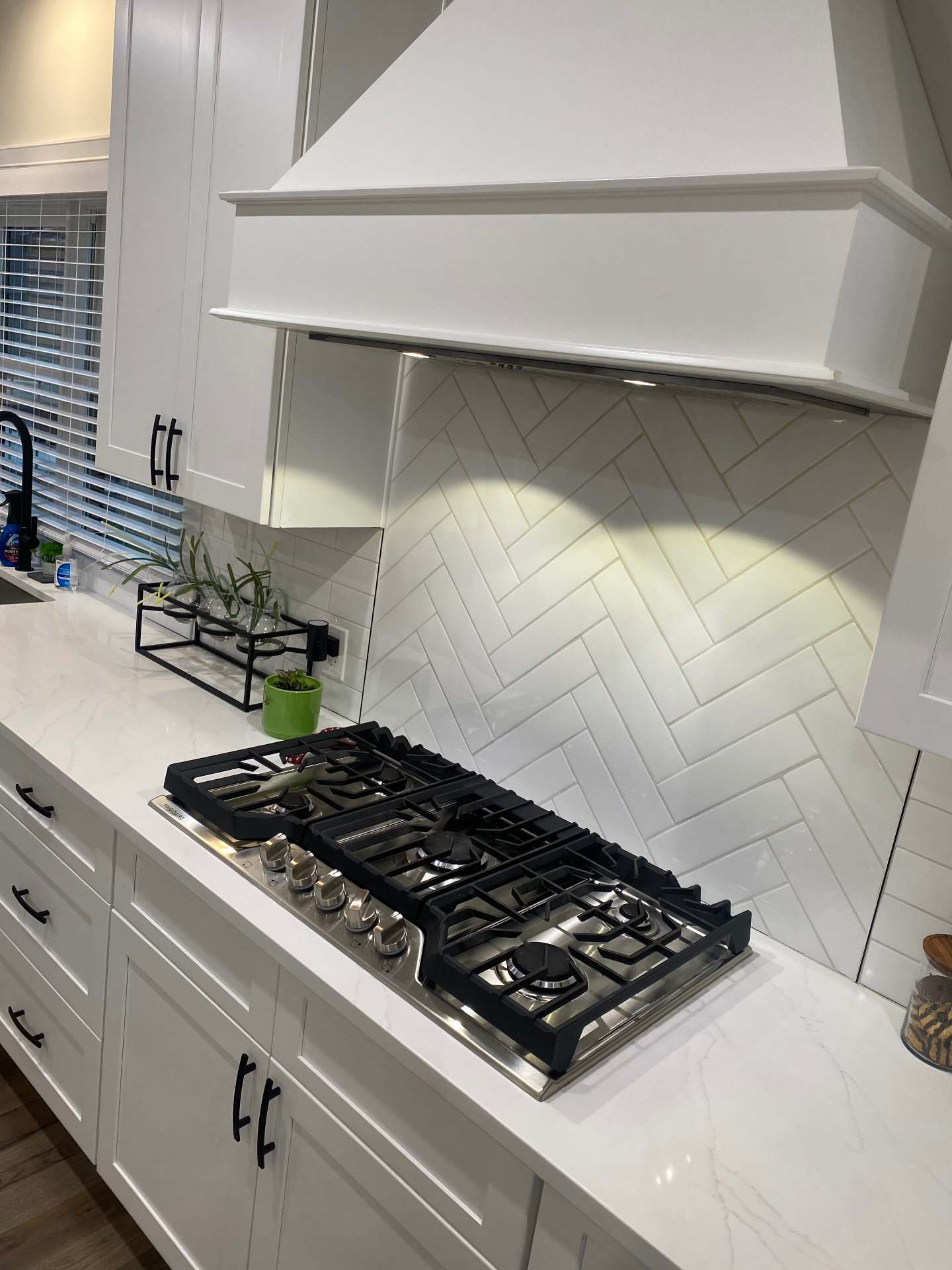 Sparkling clean white herringbone backsplash and stovetop after RealsMaster cleaning
